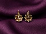une paire de boucles d'oreilles en or posées sur un tissu violet