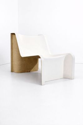 une chaise blanche posée sur un sol blanc, à côté d'une plante