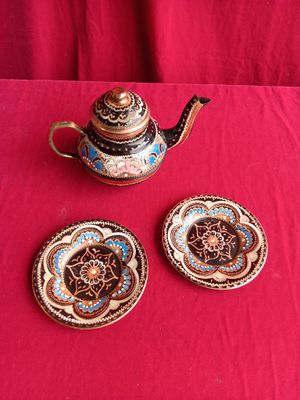 a tea pot and two small plates on a red table