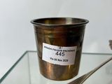 a silver cup with a spoon sitting on a glass table