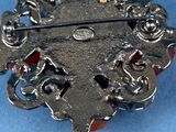 an antique silver broochle with red beads on a blue background