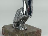 statue d'un pélican posée sur un socle en marbre, sur fond blanc
