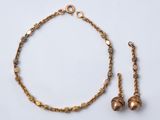 un gros plan d'un collier et d'un bracelet ornés de clochettes, posés sur une surface blanche