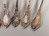 six silver spoons are lined up in a row on a table