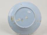 a blue and white plate on a stand on a white surface
