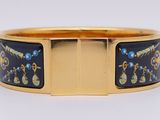 a close up of a gold bracelet with blue and green designs