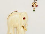 a white elephant and a gold ring on a white surface