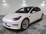 the white tesla model 3 is parked on a checkered floor