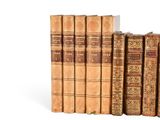 several old books are stacked on top of each other on a white surface