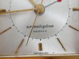 a close up of a gold clock with a red second hand