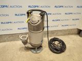 une pompe à eau argentée posée sur un sol en ciment à côté d'un tuyau d'arrosage