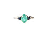 un gros plan d'une bague sertie d'une émeraude verte et d'un saphir bleu