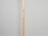 a wooden floor lamp on a checkered floor in front of a white wall