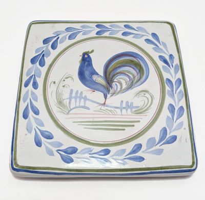 une assiette bleue et verte sur laquelle est représenté un coq