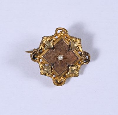 un gros plan d'une broche en or sertie d'une perle