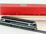 un train noir et argenté sur les rails, à côté d'une boîte rouge