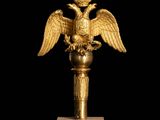 an image of a golden statue of a bird with a crown on it