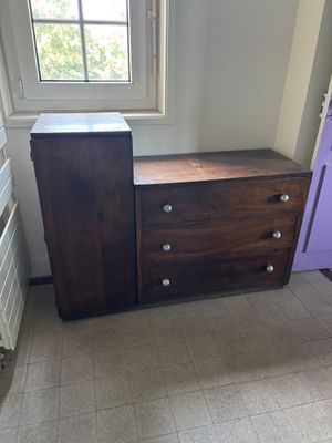 une commode dans un coin d'une pièce, avec une fenêtre en arrière-plan