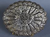 a silver plate with a flower design on it on a blue surface