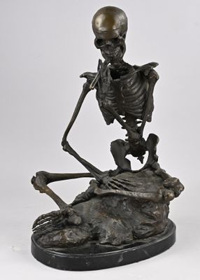 statue d'un squelette assis sur un rocher, avec un crâne posé sur son dos