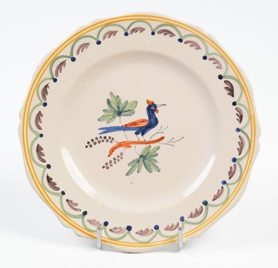 une assiette ornée d'un oiseau, posée sur un socle