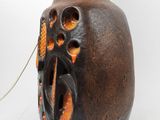 a brown vase with holes in it on a white surface