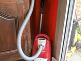 a red vacuum that is sitting on the floor next to a window