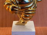 statue en or représentant un homme qui rit, posée sur un bloc de marbre