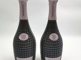 deux bouteilles de champagne posées l'une à côté de l'autre sur une surface blanche