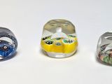 three different colored glass beads sitting on top of a white surface