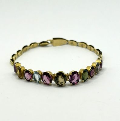 un bracelet en or avec des pierres multicolores sur fond blanc
