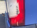 a close up of a blue truck with a red tail light