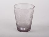 un verre transparent orné d'un motif, posé sur une surface blanche