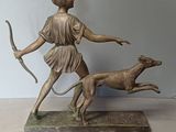 statue of a woman with a bow and a dog on a table