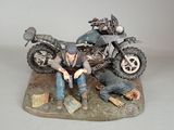 a figurine of a man sitting next to a motorcycle