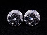 a pair of round cut diamonds on a black surface