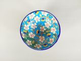 un bol bleu orné de fleurs, posé sur une table