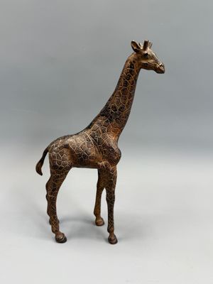 statue d'une girafe debout sur une surface blanche, avec un arrière-plan gris