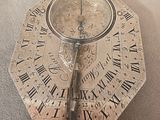 a silver clock with roman numerals on it on a table
