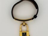 a black and gold watch with a padlock attached to it