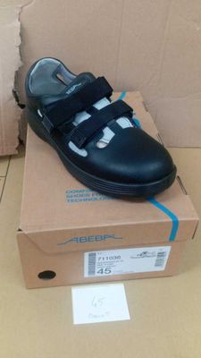 black leather school shoes with velcro straps on top of a cardboard box