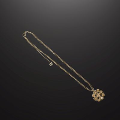un collier en or avec un pendentif en forme de fleur sur fond noir