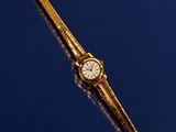 a gold watch on a blue surface