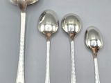 four spoons and a spoon rest on a white surface