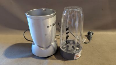 un mixeur posé à côté d'une tasse sur une table