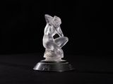 une figurine en cristal représentant une femme assise sur une surface noire