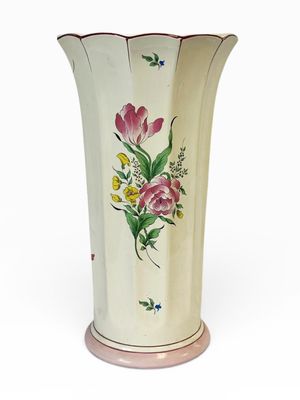 un vase avec des fleurs peintes dessus, posé sur une table