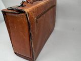 a brown leather suitcase sitting on a white surface