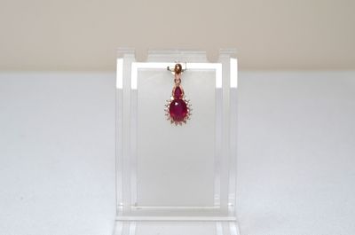 earrings in a clear display case with a red bead hanging from it