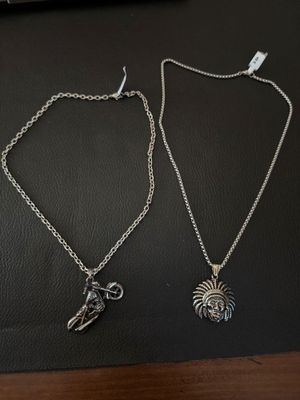 two necklaces with charms on them sitting on top of a table
